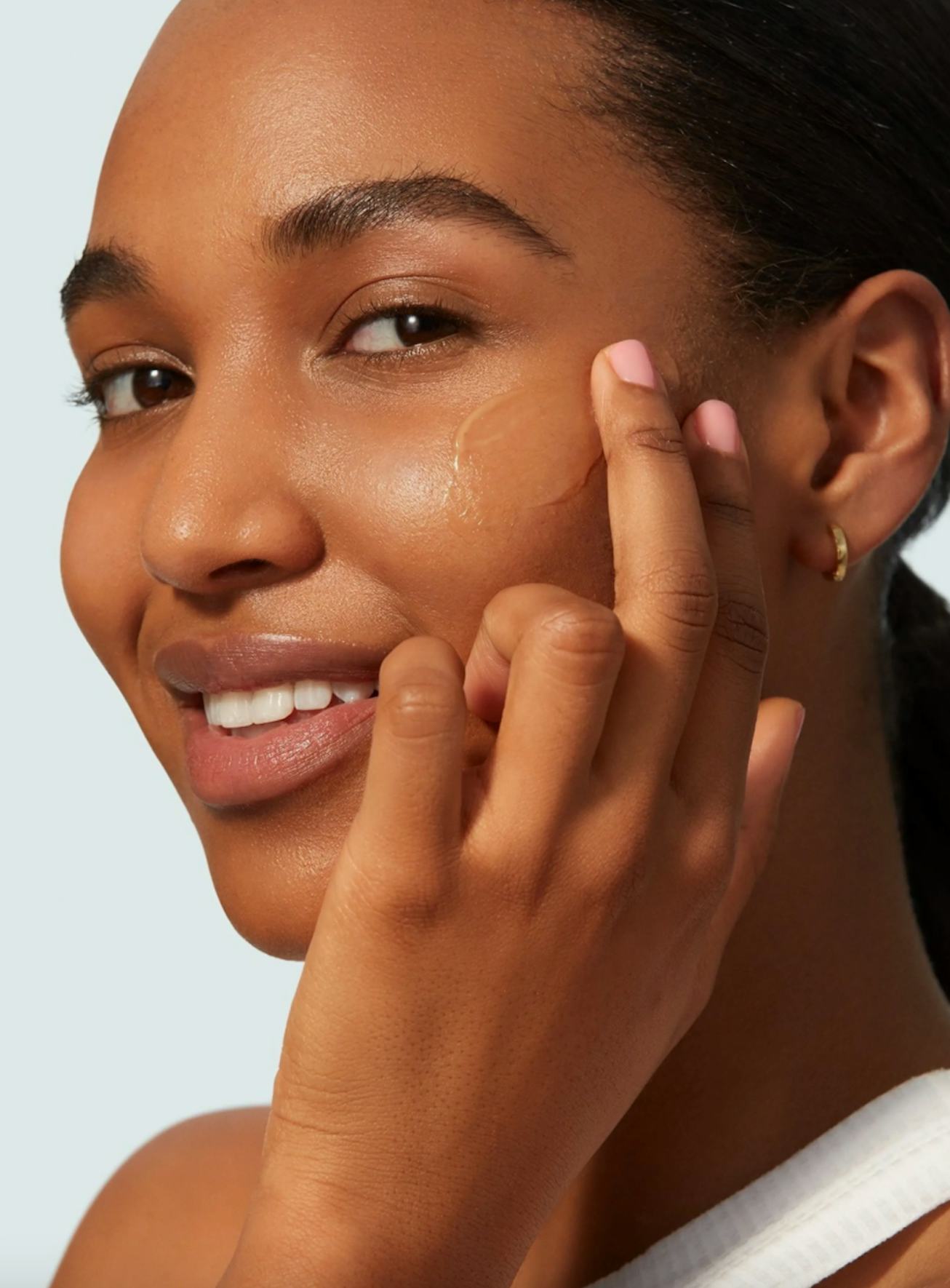 Model applies sunscreen to cheek with two fingers