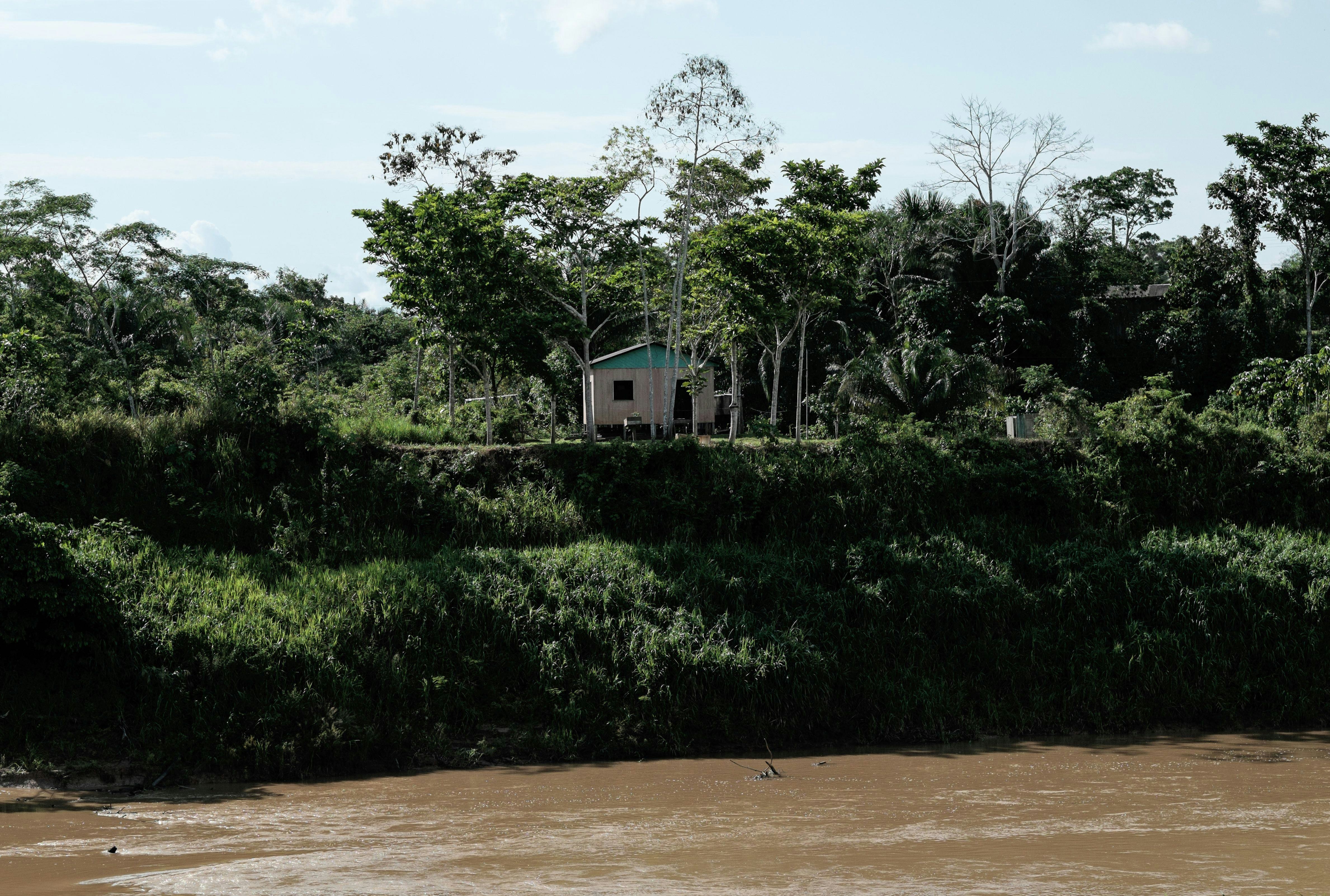 A small house sits on a riverbank in the state of Acre in Brazil.