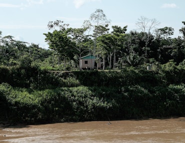 A small house sits on a riverbank in the state of Acre in Brazil.