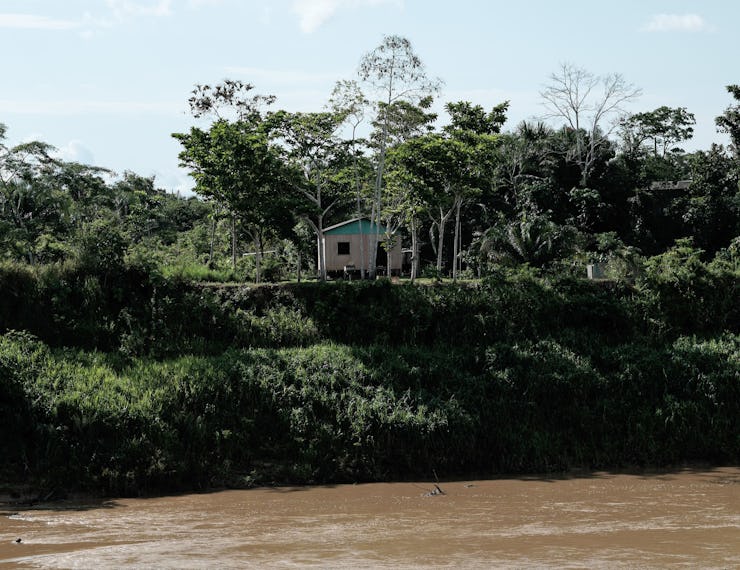 A small house sits on a riverbank in the state of Acre in Brazil.
