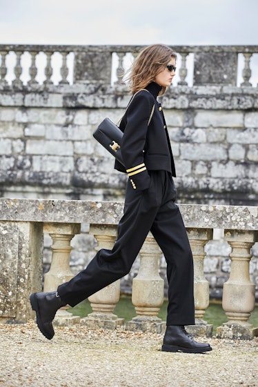 A model walking in a black Celine suit and bag