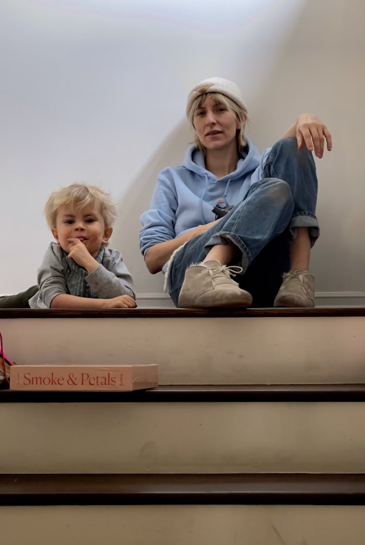 Mickey Sumner and her son, Akira, sitting on the floor at the top of a set of stairs 