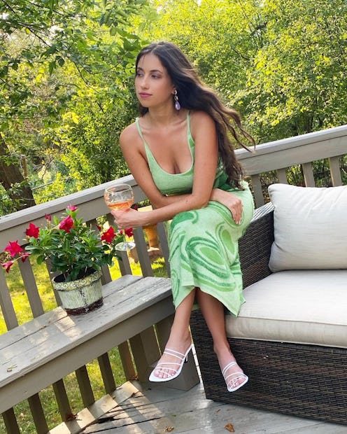 A girl with black hair sitting in a green summer dress