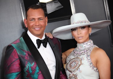 Jennifer Lopez in a white rhinestone dress and hat and Ale Rodriguez in a white shirt and a black-bu...