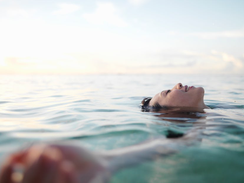 Woman floating in sea, smiling