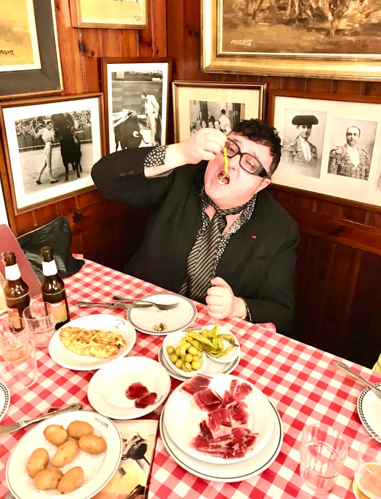 Alber Elbaz in a restaurant eating French fries with meat, olives, potatoes and bread on the table i...
