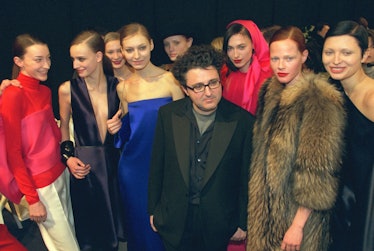Alber Elbaz posing next to a group of model backstage at a fashion show