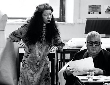 Alber Elbaz looking at designs with a woman with curly hair standing next to him in black-and-white