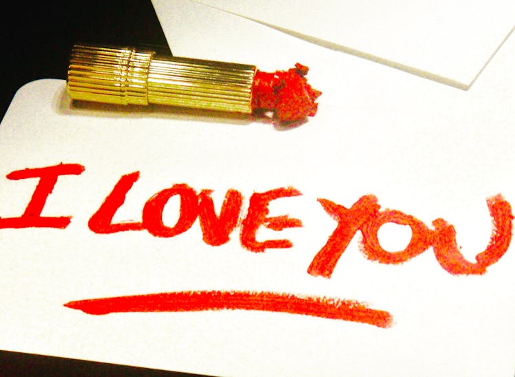 The text 'I LOVE YOU' written with a red lipstick on a white paper