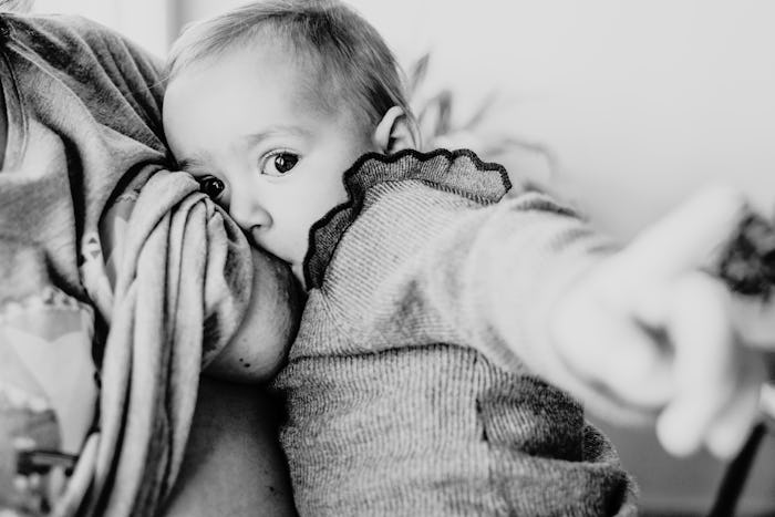 Black and white photo of a breastfeeding baby looking at the viewer