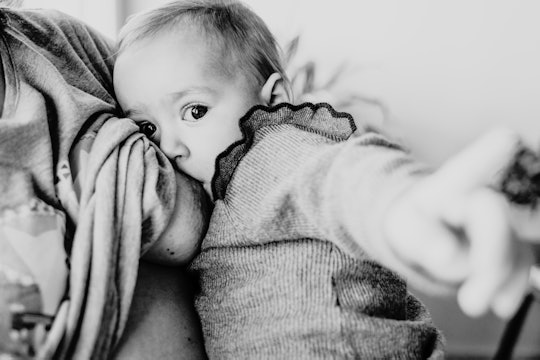 Black and white photo of a breastfeeding baby looking at the viewer