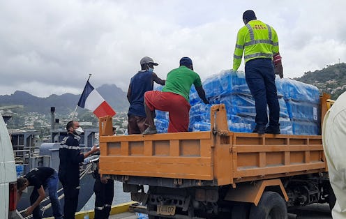 French military personnel unload aid parcels from the Floreal class French frigate Ventose on the is...