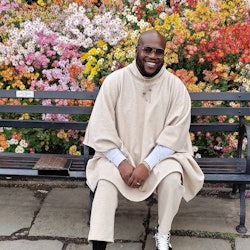 Wouri Vice in a long beige hoodie and matching pants, with a white shirt underneath 