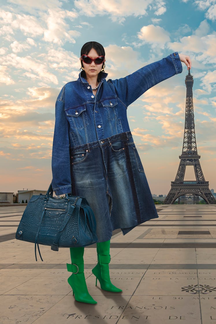 A model wearing an all-denim outfit by Balenciaga while posing in front of the Eiffel tower in Paris