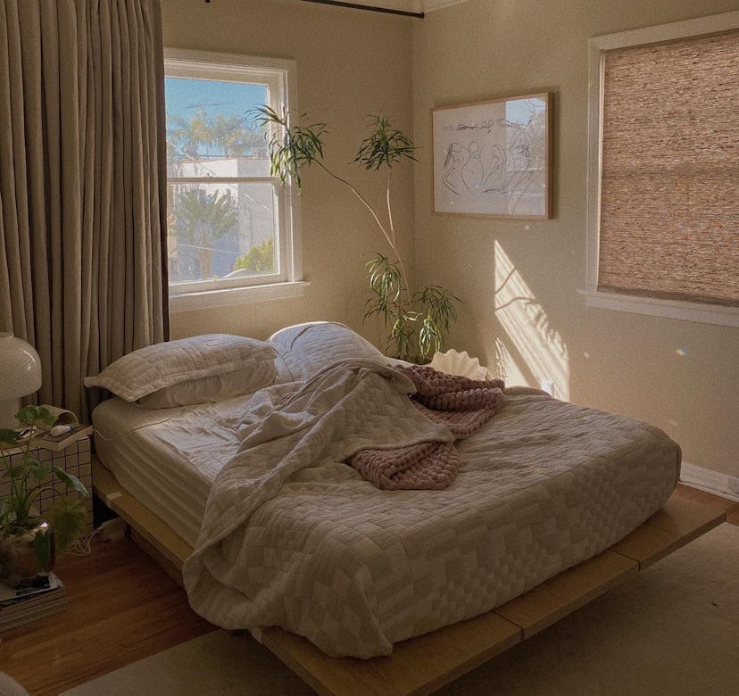 A bed with a geometric comforter against a window with the blinds drawn.