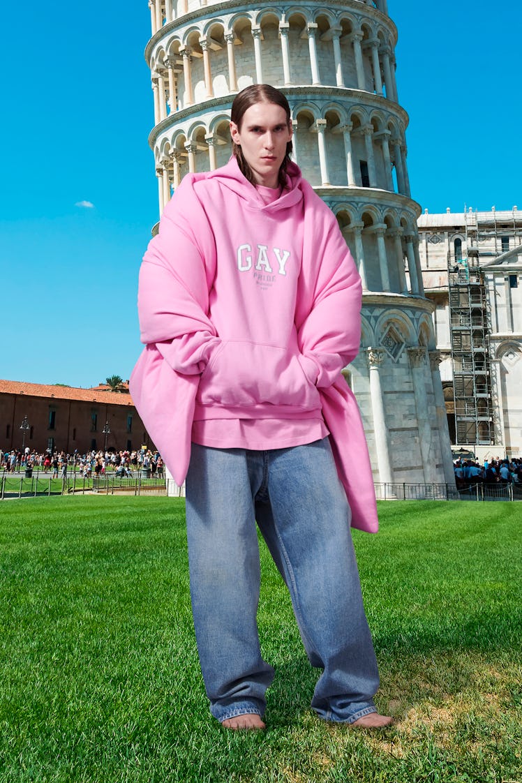A model posing in a pink oversized hoodie by Balenciaga in front of the Pisa tower
