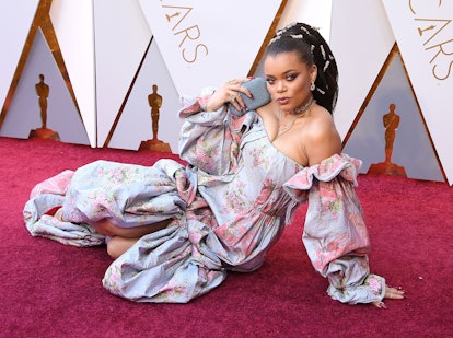 Andra Day at the Academy Awards 2018 in a floral strapless gown with long sleeves, posing on the gro...
