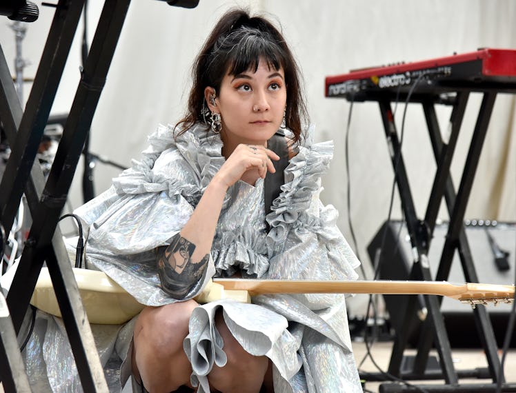 Michelle Zauner sitting and holding a guitar on her lap