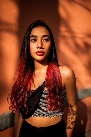 Young woman shaded with orange background during the blood moon, wondering its spiritual meaning, bl...