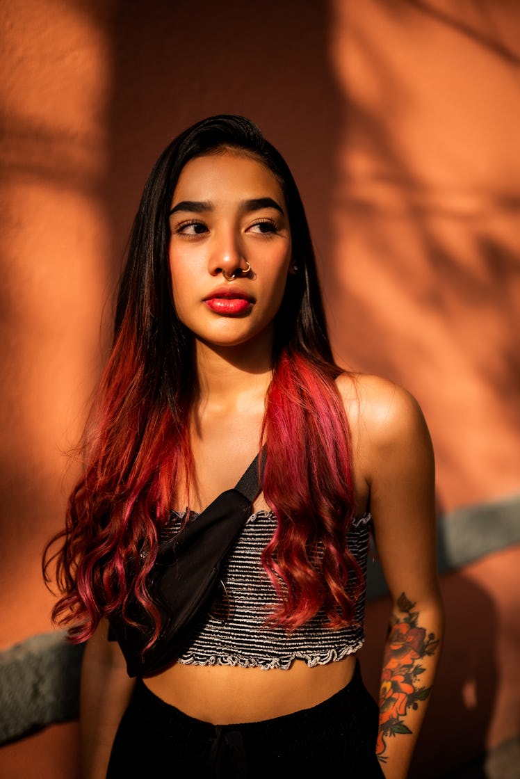 Young woman shaded with orange background during the blood moon, wondering its spiritual meaning, bl...