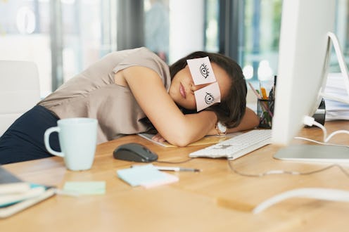 Shot of a tired businesswoman napping at her desk with adhesive notes on her eyes