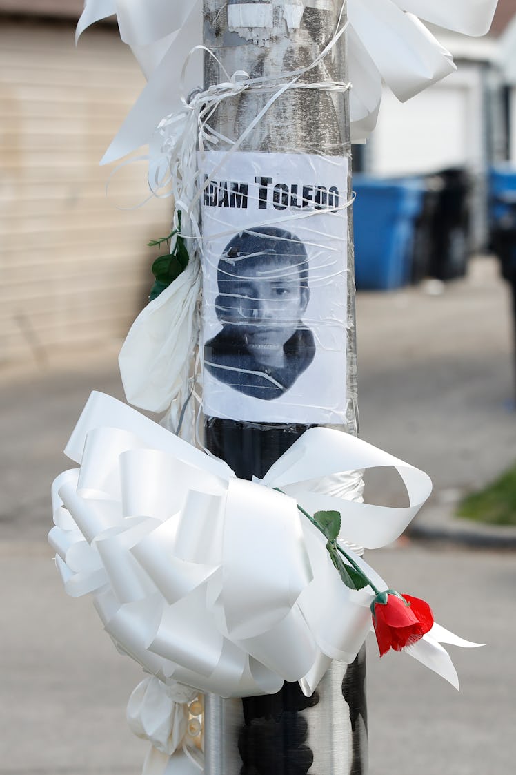 A sign featuring Adam Toledo's face is pasted to a telephone pole, along with a white ribbon and a r...