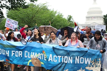A group of climate activists protesting in favor of action against climate change and holding a blue...