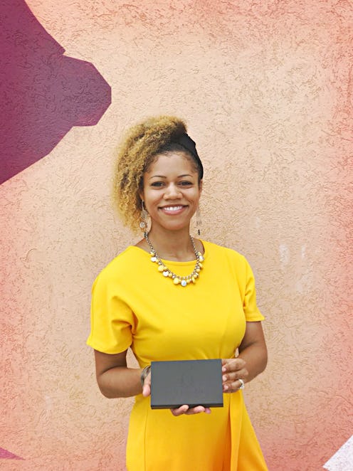 Chavalia Dunlap-Mwamba smiling in a yellow dress holding a fragrance