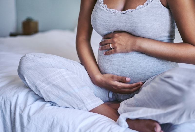 Pregnant Black woman holding her stomach.