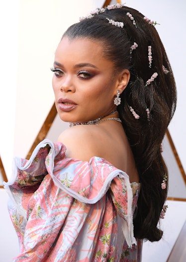 Andra Day with floral accessories in her ponytail and in a floral dress 