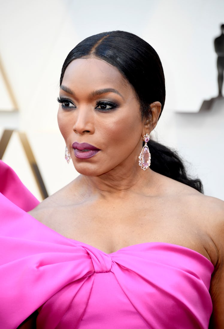 Angela Bassett with her hair in a low ponytail and in a pink dress with a bow across the top