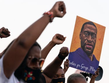 People raising their fists next to a portrait of George Floyd