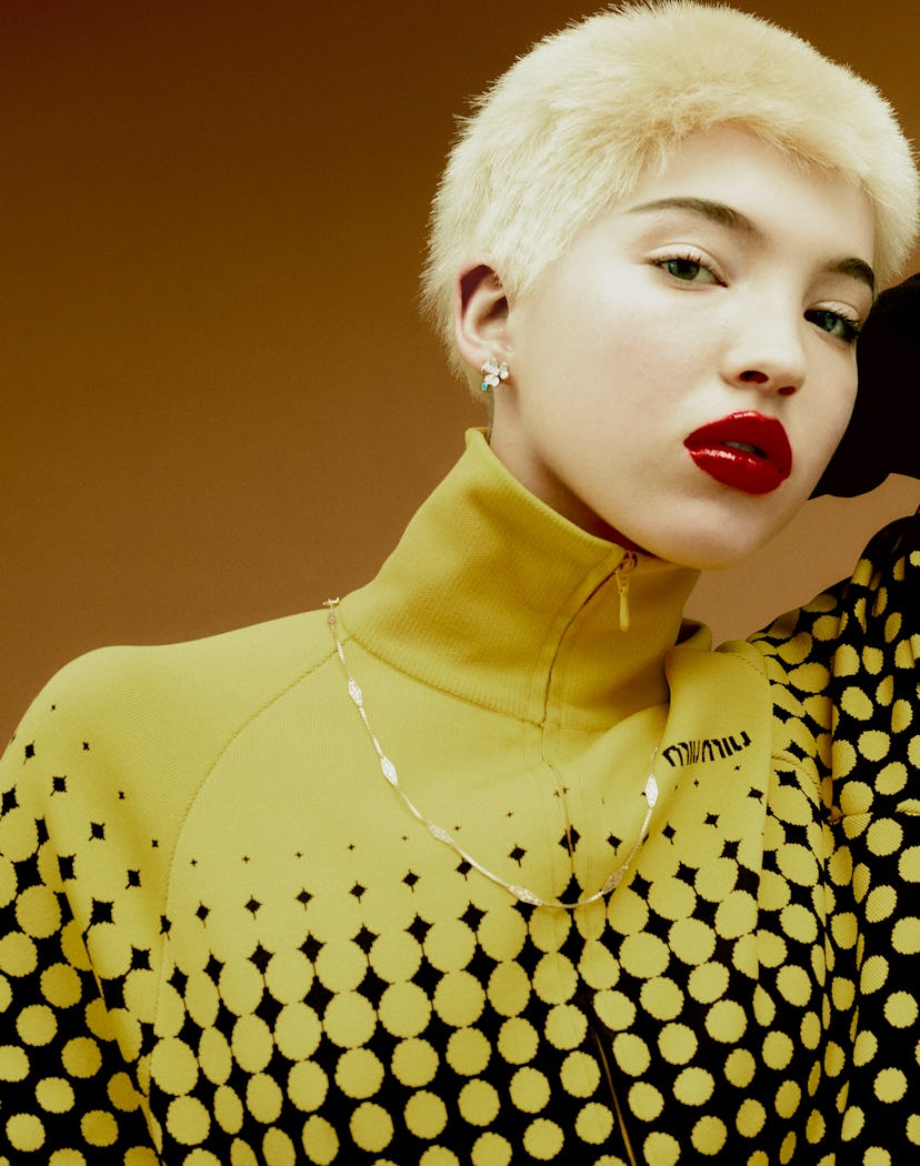 A blonde model wearing a yellow-black hoodie and a classic gold chain necklace with a twist