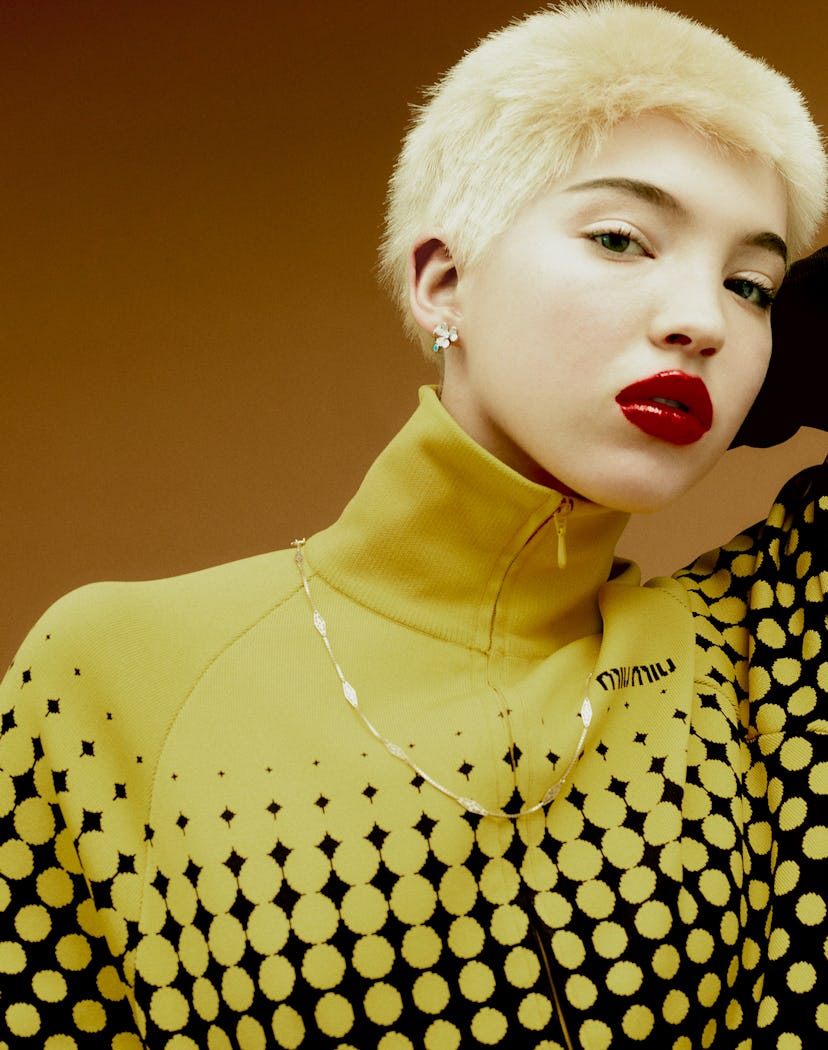 A blonde model wearing a yellow-black hoodie and a classic gold chain necklace with a twist