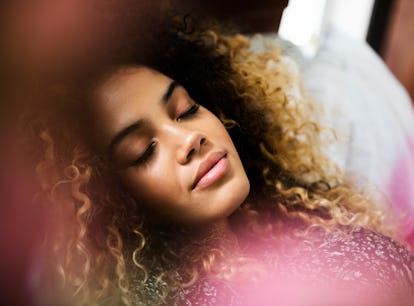 Young woman wearing a pink sweater, relaxing as she learns the spiritual meaning of the 2022 pink mo...