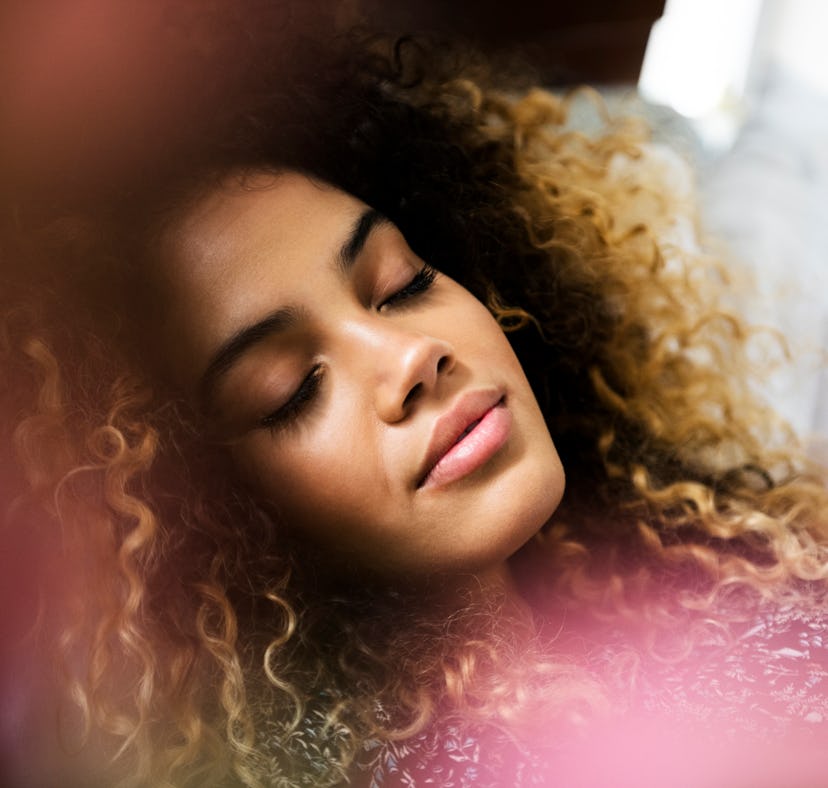 Young woman wearing a pink sweater, relaxing as she learns the spiritual meaning of the 2022 pink mo...