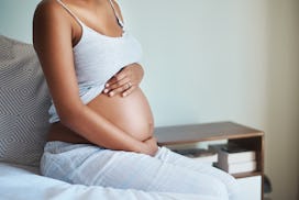 Pregnant woman sitting on edge of bed