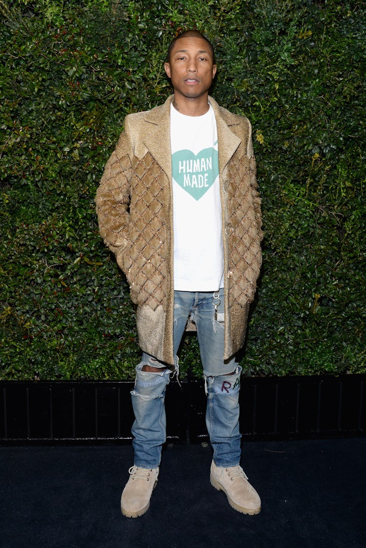Pharrell Williams in a white shirt, beige coat and blue denim jeans at Chanel’s Pre-Oscars Dinner