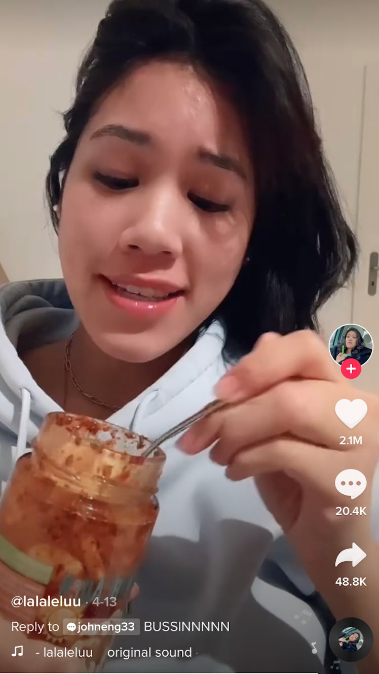 A woman eats spicy pickled garlic from a jar on TikTok.