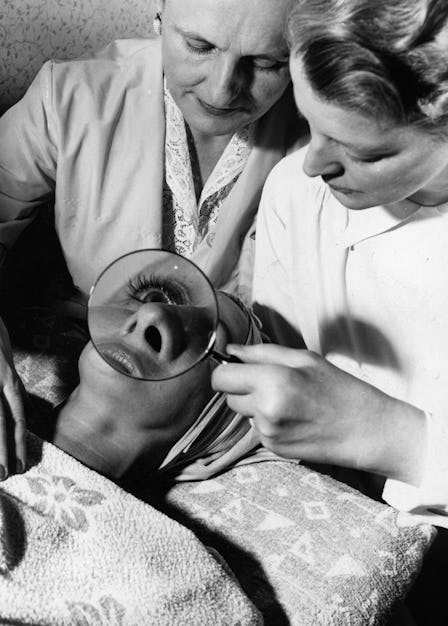 Doctor examining the woman's skin with a magnifying glass