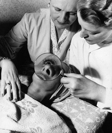 Doctor examining the woman's skin with a magnifying glass