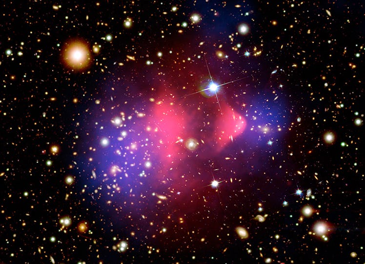 Composite image shows galaxy cluster 1E 0657-556 through multiple wavelengths. Hot gas, shown in pin...