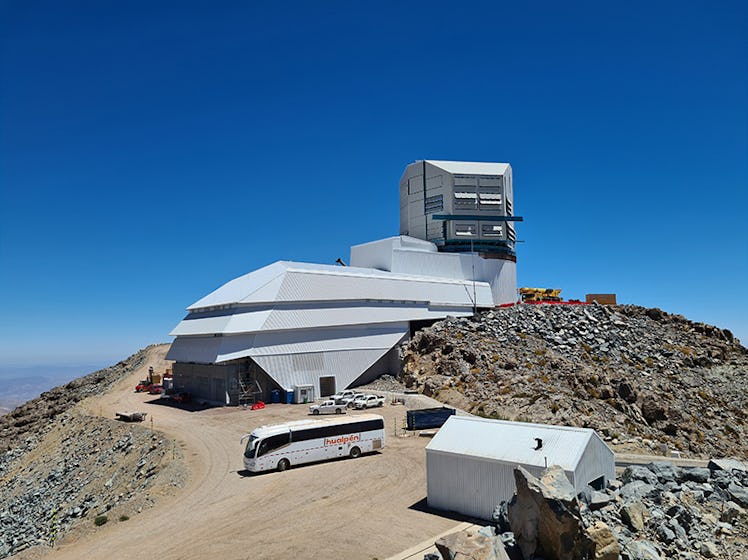 Photo shows the large summit facility building housing the telescope being built atop a mountain nea...