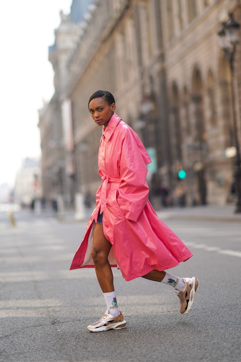 PARIS, FRANCE - MARCH 09: Emilie Joseph @in_fashionwetrust wears a neon pink long trench shiny coat ...