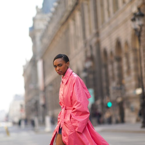PARIS, FRANCE - MARCH 09: Emilie Joseph @in_fashionwetrust wears a neon pink long trench shiny coat ...