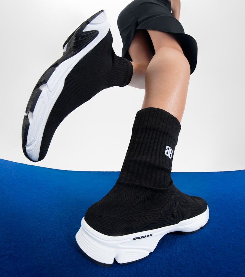 Model wearing Balenciaga black sneakers.