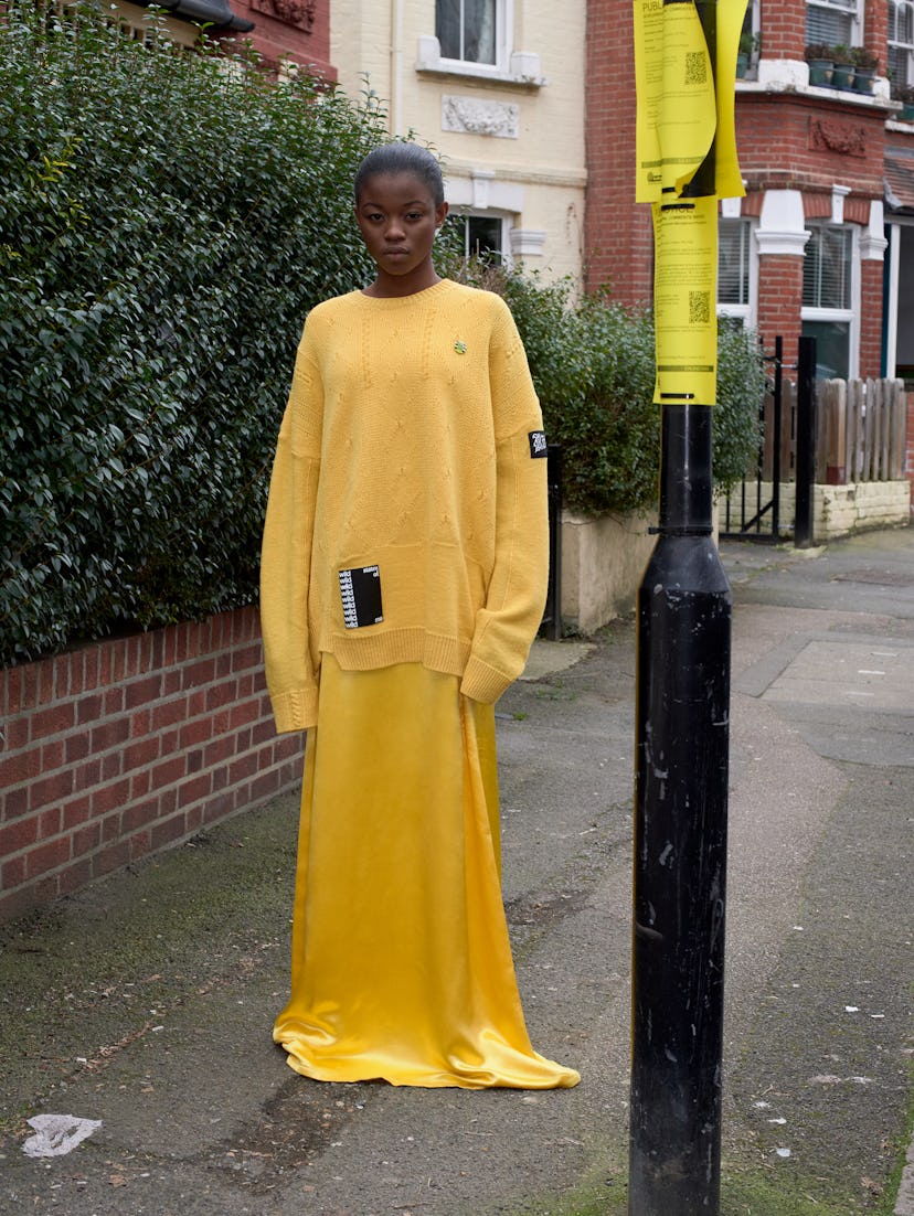A model posing in a yellow sweater and yellow dress
