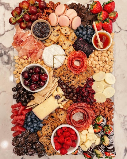 Grazing board full of cheese, fruit, and chocolate
