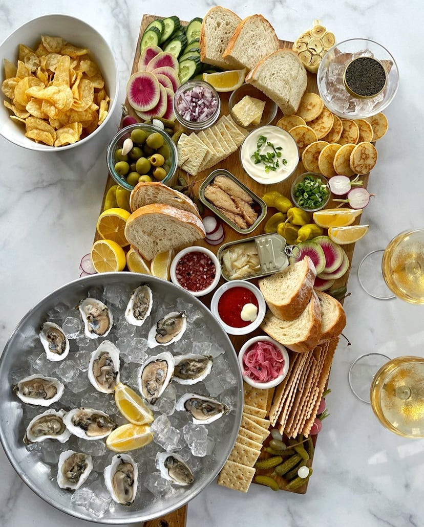 Grazing board with oyster, bread, vegetables, and caviar