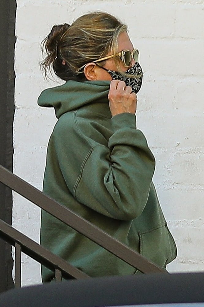 Jennifer Aniston covers her face with a mask while leaving a skincare salon in Beverly Hills with he...